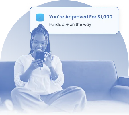 Happy woman sitting on a couch looking at her phone with a notification saying she’s approved for a $1,000 loan